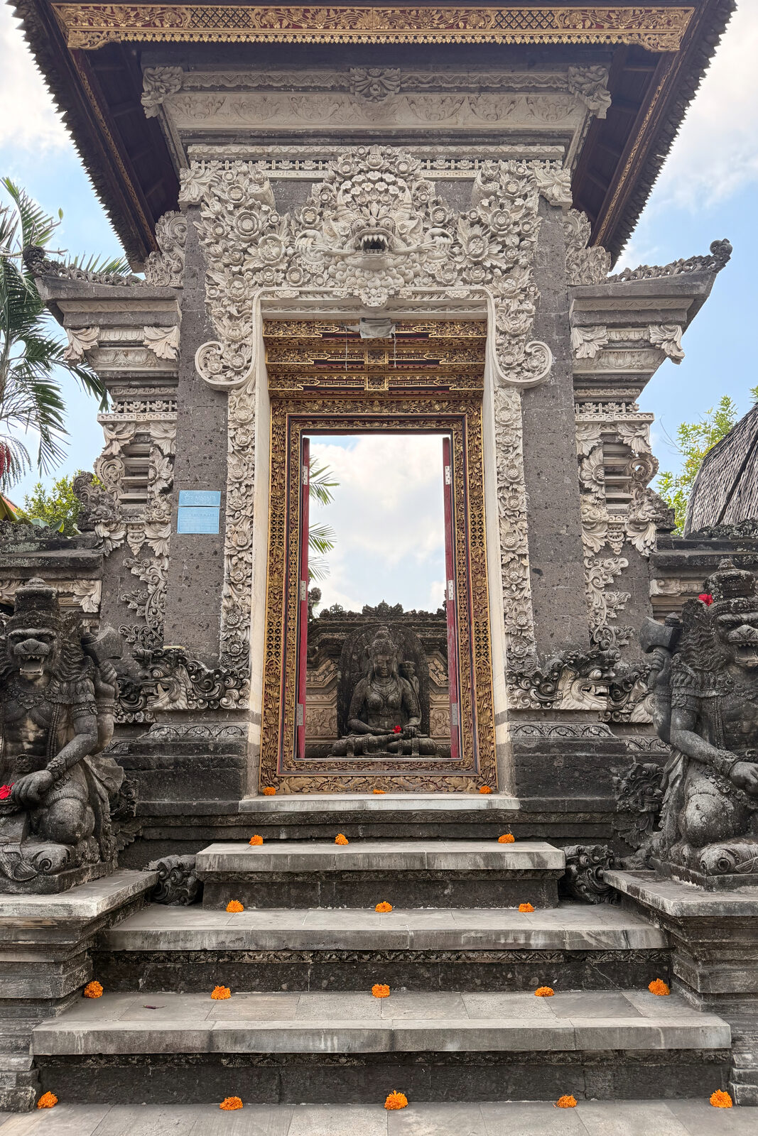 A carved stone gate with a statue framed in its doorway.