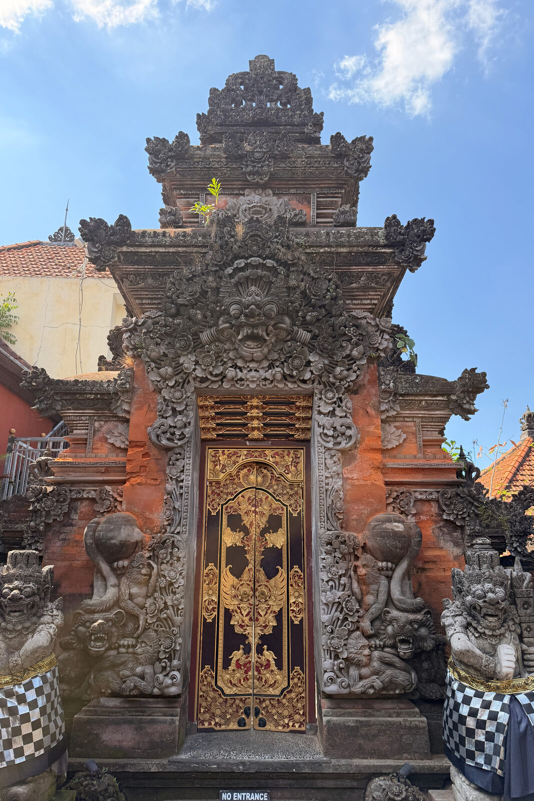 A brick and stone gate with a gilded door and a No Entrance sign.
