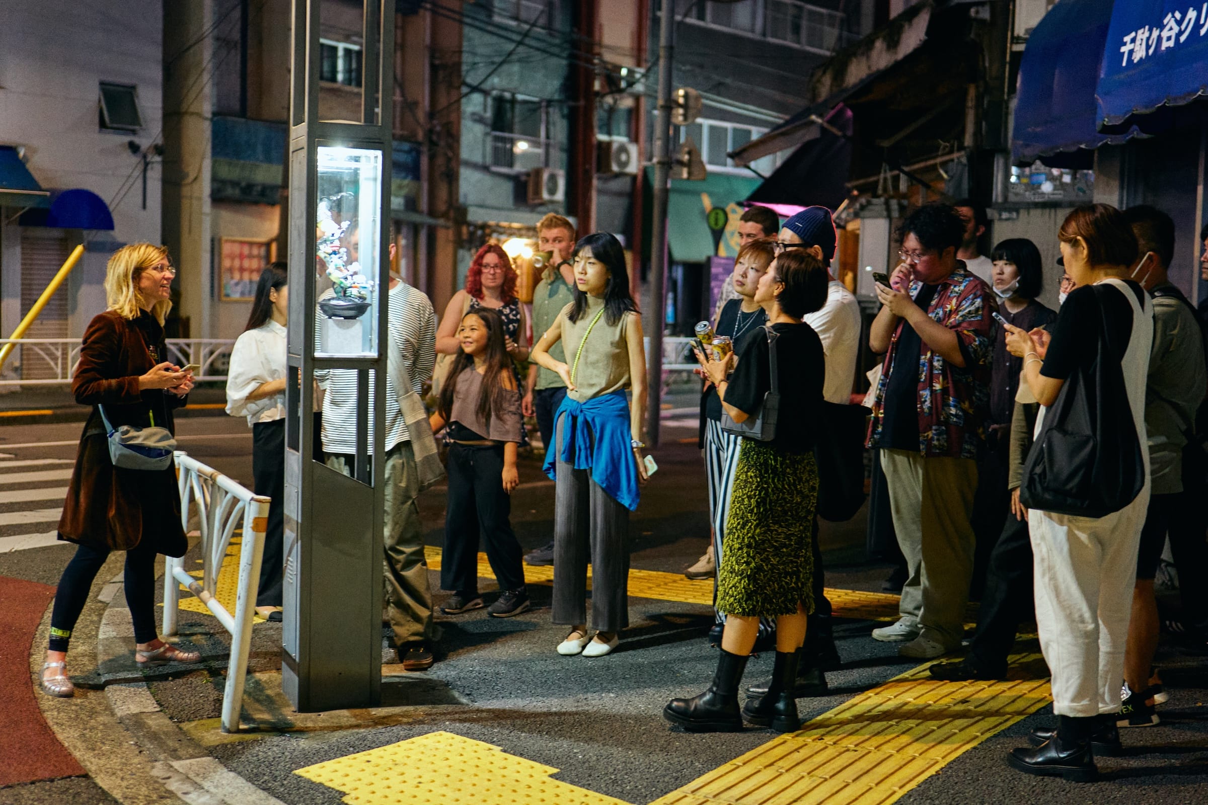 People gathered around street lamp listening to artist