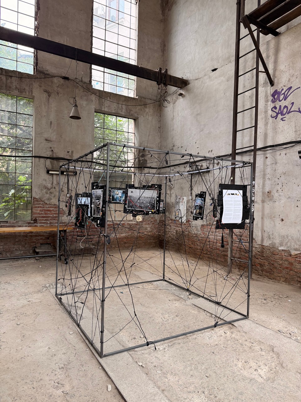 The cube and its network of cables against the windows and brick walls